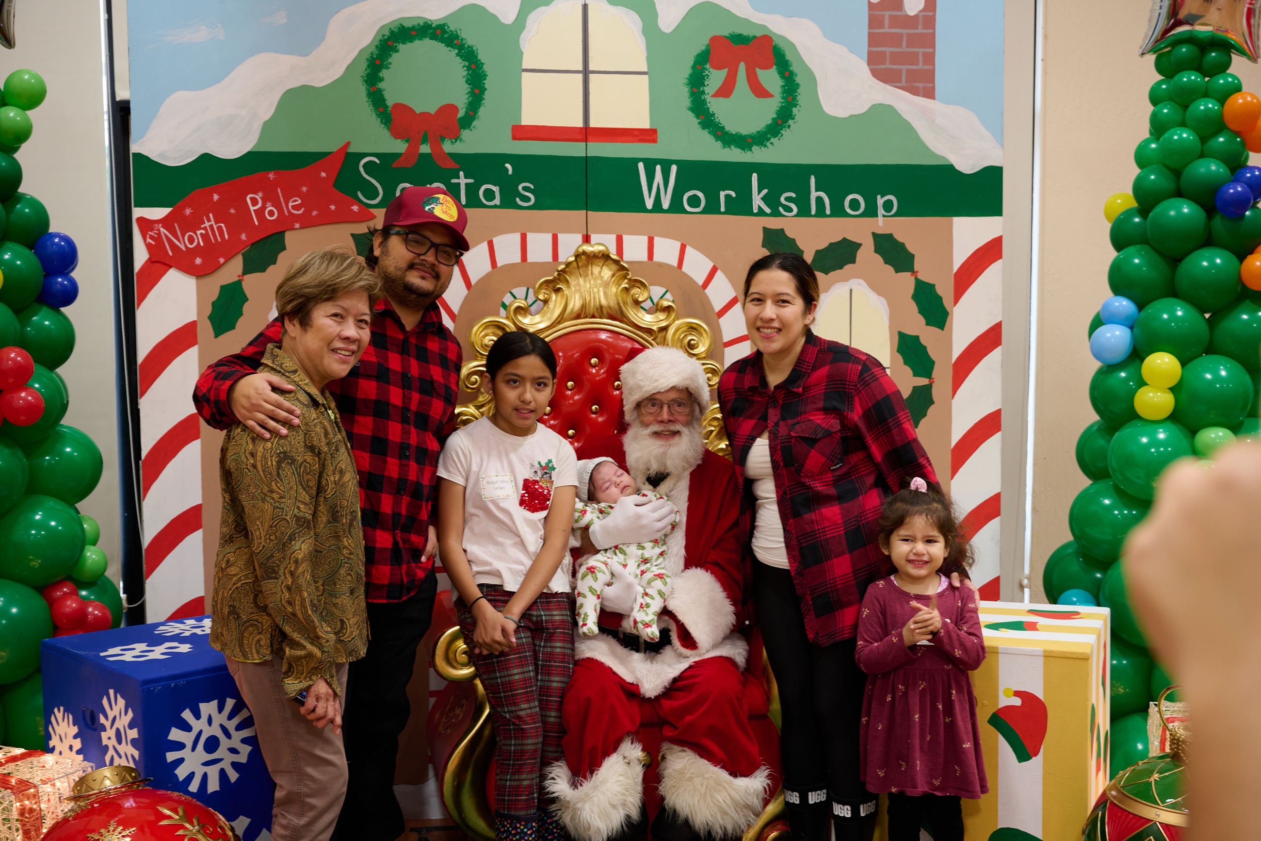 Festive family with mom, dad, two girls, a baby and grandma pose with Santa 