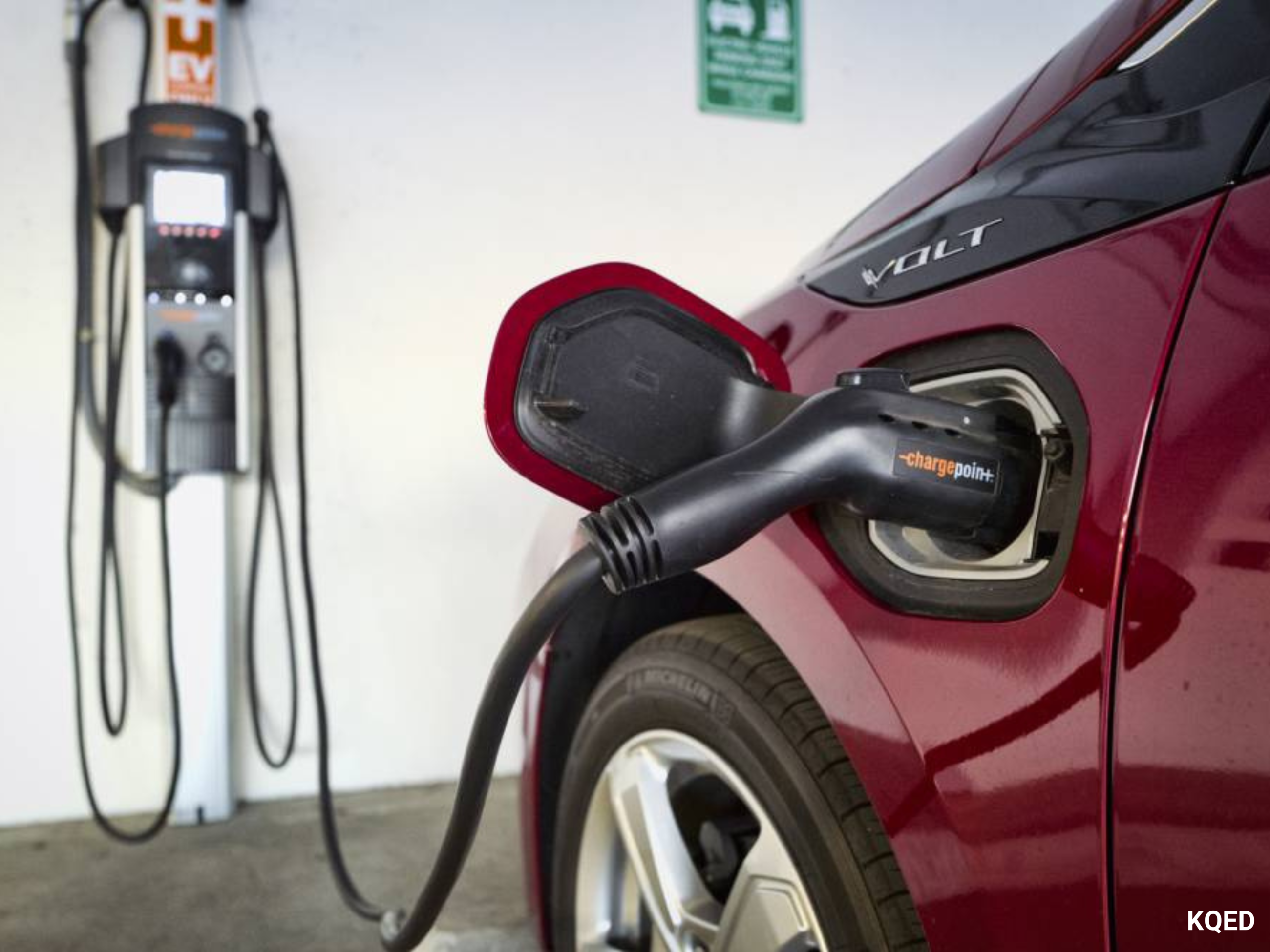 Red electric vehicle charging at wall charger