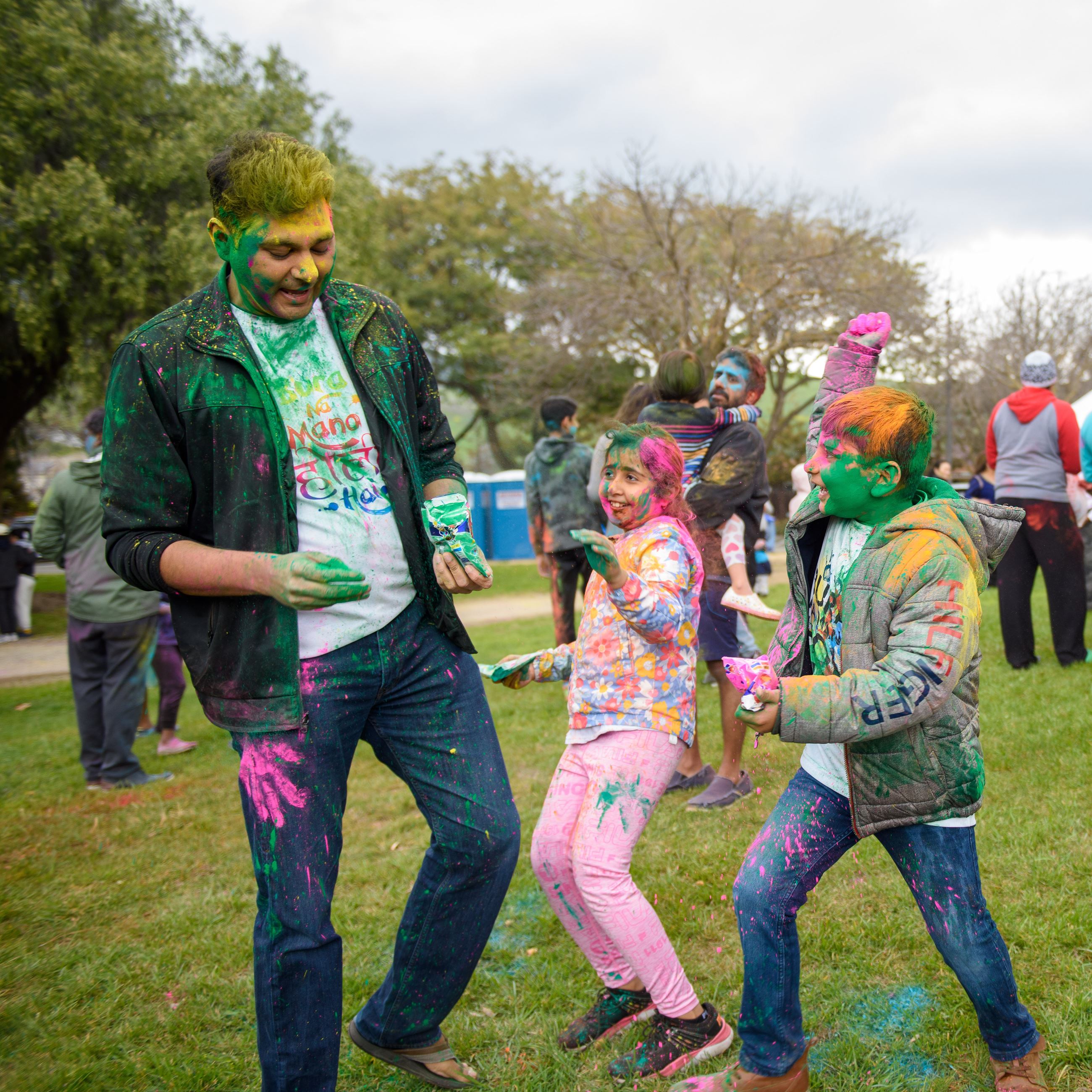 A dad and two children play with colored powder.