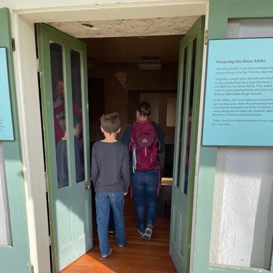 A  mother and boy walk through the weather door of the historic Alviso Adobe.